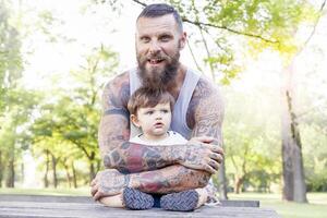 tatuado padre tener divertido con su hijo en el parque foto