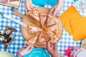 group of friends eating pizza. Top view of four hands taking pizza slices photo