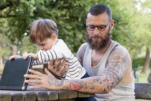 tattooed dad have fun with his son and laptop photo