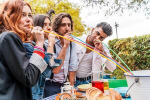 grupo de multicultural amigos teniendo divertido a el jardín fiesta succión cerveza desde vistoso pajitas foto