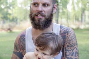 tattooed father have fun with his son in the park photo