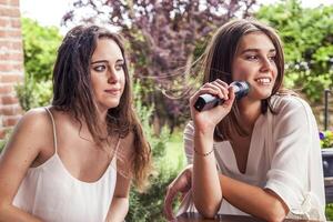 dos joven hembra amigos teniendo divertido canto un nuevo canción foto