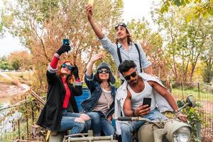 group of best friends take a selfie riding a vintage motorcycle with sidecar photo