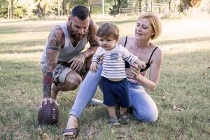 young couple with child having fun at the park with rugby ball photo