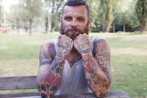 retrato de barbado hombre con codos en el mesa en el parque foto