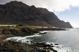 Volcanic black beach and Rough rocky cliffs on the island of Tenerife. Rocks, volcanic rock, Atlantic Ocean photo