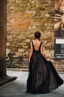 un hermosa elegante novia en un negro vestir camina mediante florencia, un modelo en un negro vestir en el antiguo ciudad de Italia foto