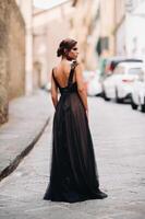 un hermosa elegante novia en un negro vestir camina mediante florencia, un modelo en un negro vestir en el antiguo ciudad de Italia foto