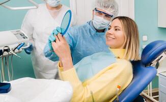 el dentista muestra el cliente el resultados de su trabajo en el espejo foto