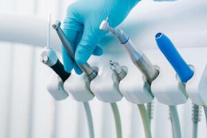 un dentista vistiendo guantes en el dental oficina sostiene un herramienta antes de trabajando foto