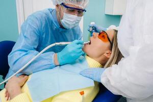 A female patient in dental glasses treats teeth at the dentist with ultraviolet light. dental fillings photo