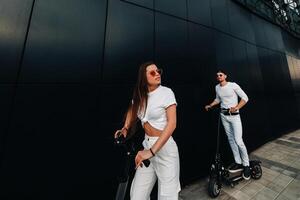 A girl and a guy are walking on electric scooters around the city, a couple in love on scooters. photo