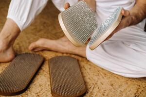 un hombre sostiene en su manos tableros con uñas para yoga clases foto