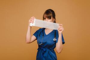un hembra médico en un blanco Saco sostiene retorcido gasa vendajes para vendaje heridas en un marrón antecedentes foto