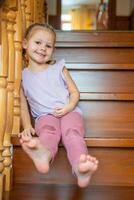 Cute Little girl is playing on stairs at home. Dangerous situation at home. Child safety concept. photo