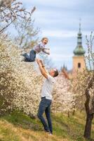 padre y hija teniendo un divertido juntos debajo un floreciente árbol en primavera parque petrin en praga, Europa foto