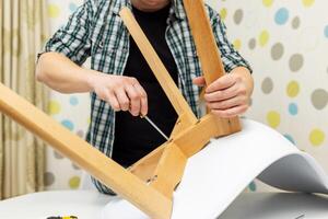 Self-assembly furniture concept. The young man himself assembling chairs photo