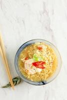 Mie Kuah Telur for Sahur in Ramadan, Instant Noodle Soup Served on Glass Bowl with Poached Egg and Chili. photo