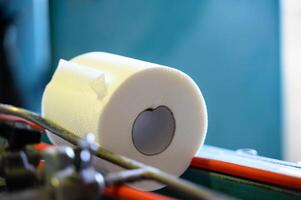 Toilet paper rolls moving along the conveyor belt. Old Greek factory for the production of paper rolls for hygiene. Manufacture of paper towels and toilet paper. Close up view. Selective focus photo