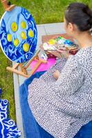 asiático joven mujer pintura imagen de limones en azul cobija en hogar terraza. alto calidad foto