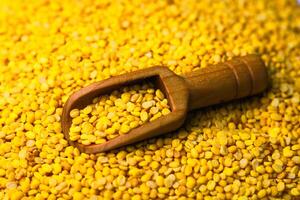 Fried mung bean in a wooden scoop on a pile of fried mung bean background photo