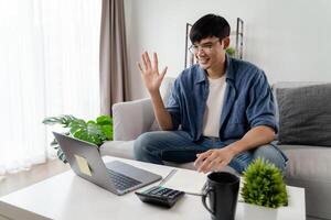 el hombre en casual ropa trabajando con un computadora portátil, computadora, inteligente teléfono, calculadora sentado en el sofá en el vivo habitación a hogar, trabajando desde hogar concepto. foto