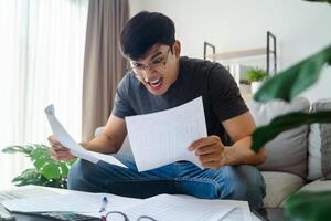 el hombre sensación enojado pánico cuando él leyendo factura documentos, crédito tarjeta deuda, préstamos, impuestos. foto