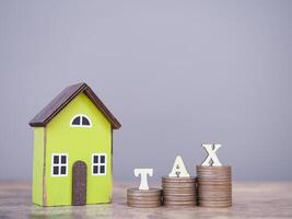 Miniature house and Wooden blocks with the word TAX on stack of coins. The concept of payment tax for house, Property investment, House mortgage, Real estate photo
