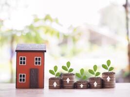 Miniature house and plants growing up on stack of coins. The concept of saving money for house, Property investment, House mortgage, Real estate. photo