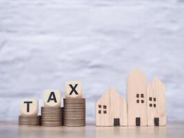 Miniature house and Wooden blocks with the word TAX on stack of coins. The concept of payment tax for house, Property investment, House mortgage, Real estate photo