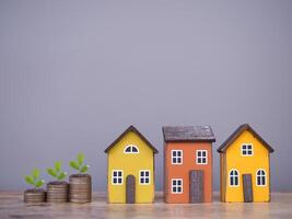 Miniature house and plants growing up on stack of coins. The concept of saving money for house, Property investment, House mortgage, Real estate. photo