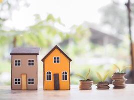 Miniature house and plants growing up on stack of coins. The concept of saving money for house, Property investment, House mortgage, Real estate. photo