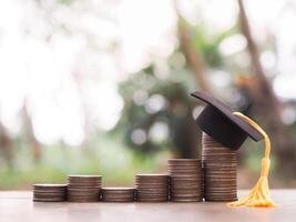 Graduation hat on stack of coins. The concept of saving money for education, student loan, scholarship, tuition fees in future photo