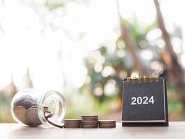 2024 desk calendar and stack of coins. The concept of saving money, Financial, Investment and Business growing in year 2024. photo