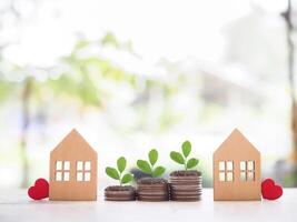 Miniature house and plants growing up on stack of coins. The concept of saving money for house, Property investment, House mortgage, Real estate. photo