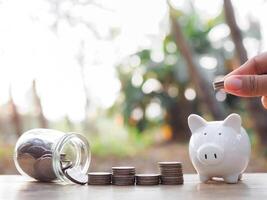 Close up hand putting coin into piggy bank and stack of coins. The concept of saving money, Financial, Investment and Business growing. photo