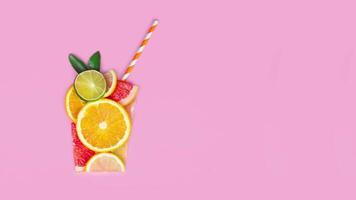 Creative flat lay juice concept. Sliced citrus orange, lime, grapefruit, lemon, fruits make juice glass shape flat lay pink background video stopmotion animation copy space for your text