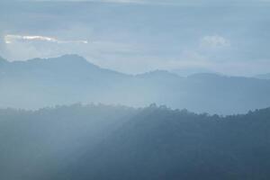 Sun rays filter through the clouds in hills of the valley illuminated by the sun's rays filtering through the clouds photo