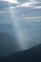 Sun rays filter through the clouds in hills of the valley illuminated by the sun's rays filtering through the clouds photo