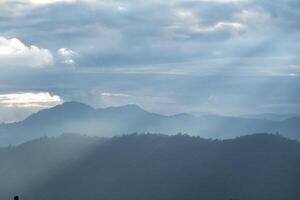 Sun rays filter through the clouds in hills of the valley illuminated by the sun's rays filtering through the clouds photo