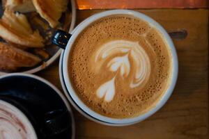 latté Arte y café tazas con canela en el mesa, acompañado por platillo, cuchara, y azúcar un encantador Mañana bebida escena a el café foto