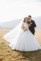 A young bride and groom tenderly embrace in the rays of the autumn sun. Tender and beautiful young girl bride. A man kisses his beloved. Against the background of a beautiful garden photo