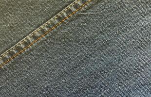 Detailed abstract texture of dark blue denim cloth. Background image of old used denim trousers fabric photo