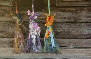 Three different brooms of witches stand at the old wooden hut house photo