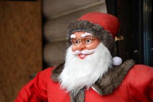 Santa claus big plastic figure with classic santa clothes close to wooden house photo