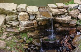 Close up of a small waterfall spilling over moss covered rocks in regional park. Handmade river waterfall photo