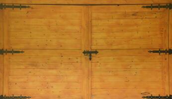 The texture of old wooden gates, old made of yellow treated wood with metal black door hinges photo