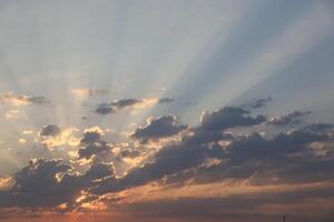 Beautiful sunrise with warm orange sunlight and beams through blue sky photo