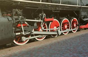 ruedas de la vieja locomotora de vapor negra de la época soviética. el lado de la locomotora con elementos de la tecnología giratoria de trenes antiguos foto