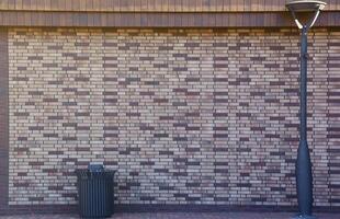 Dark brick wall pattern with masonry. Background texture modern stone wall with lamp post and street trash can photo